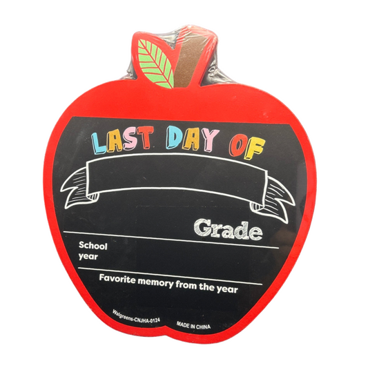 Red apple-shaped sign with 'Last Day of School' text on a black background