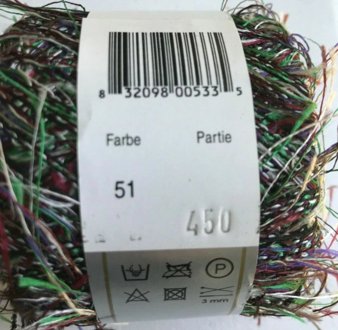 Multicolored yarn ball with a label showing a barcode and text.