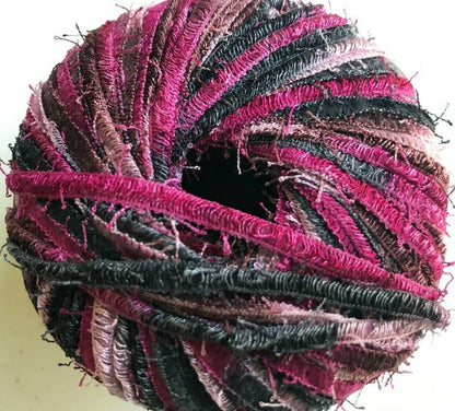 Multicolored yarn ball with pink and black patterns on a white background