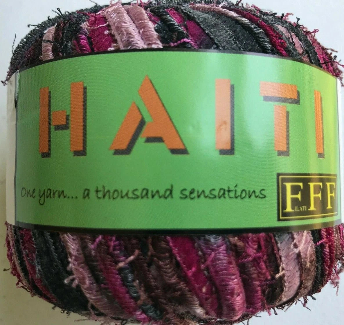 Multicolored yarn ball with a green label featuring the brand name 'HATI'.