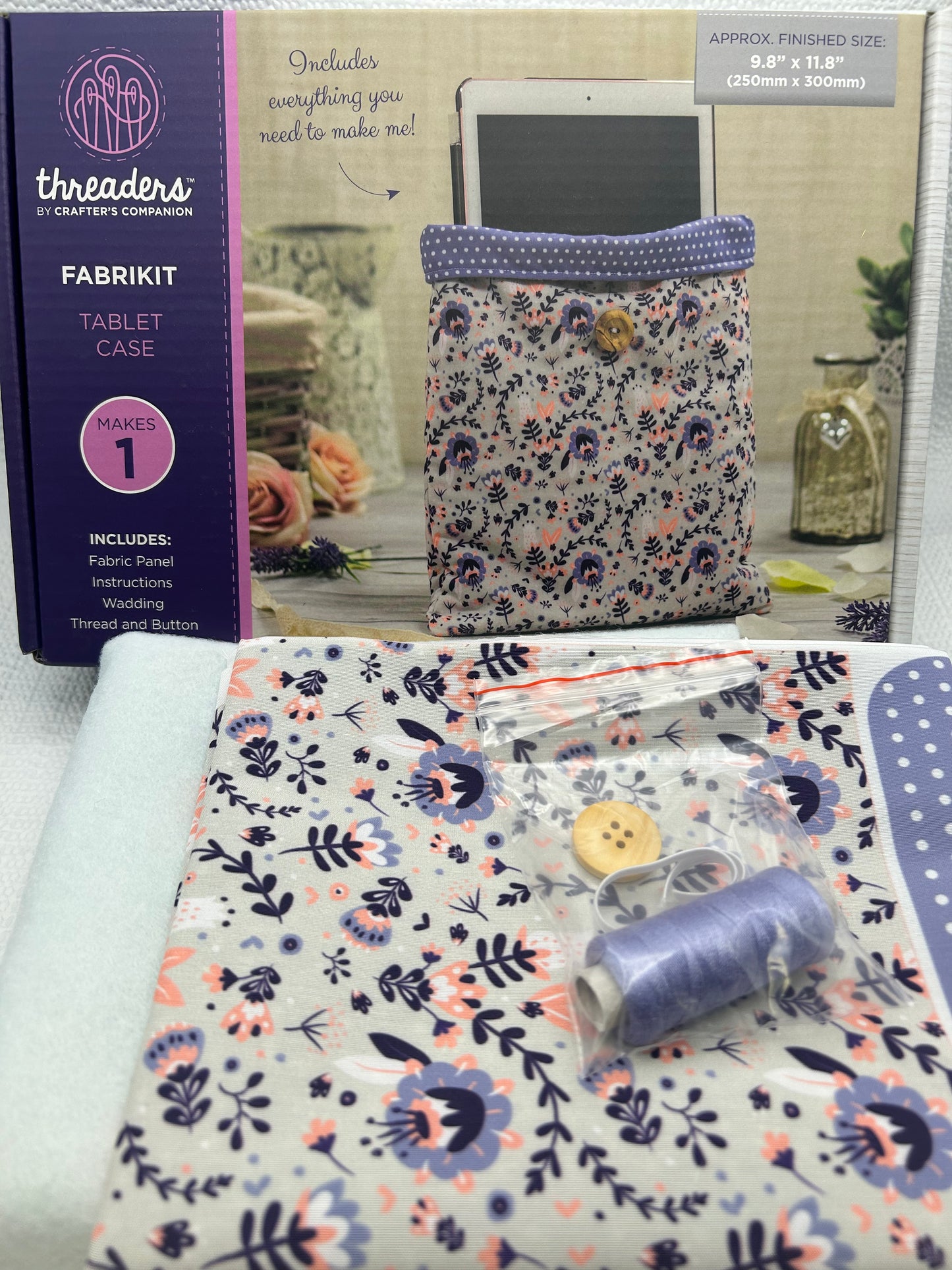 Fabric kit with floral patterned paper and sewing tools on a white surface