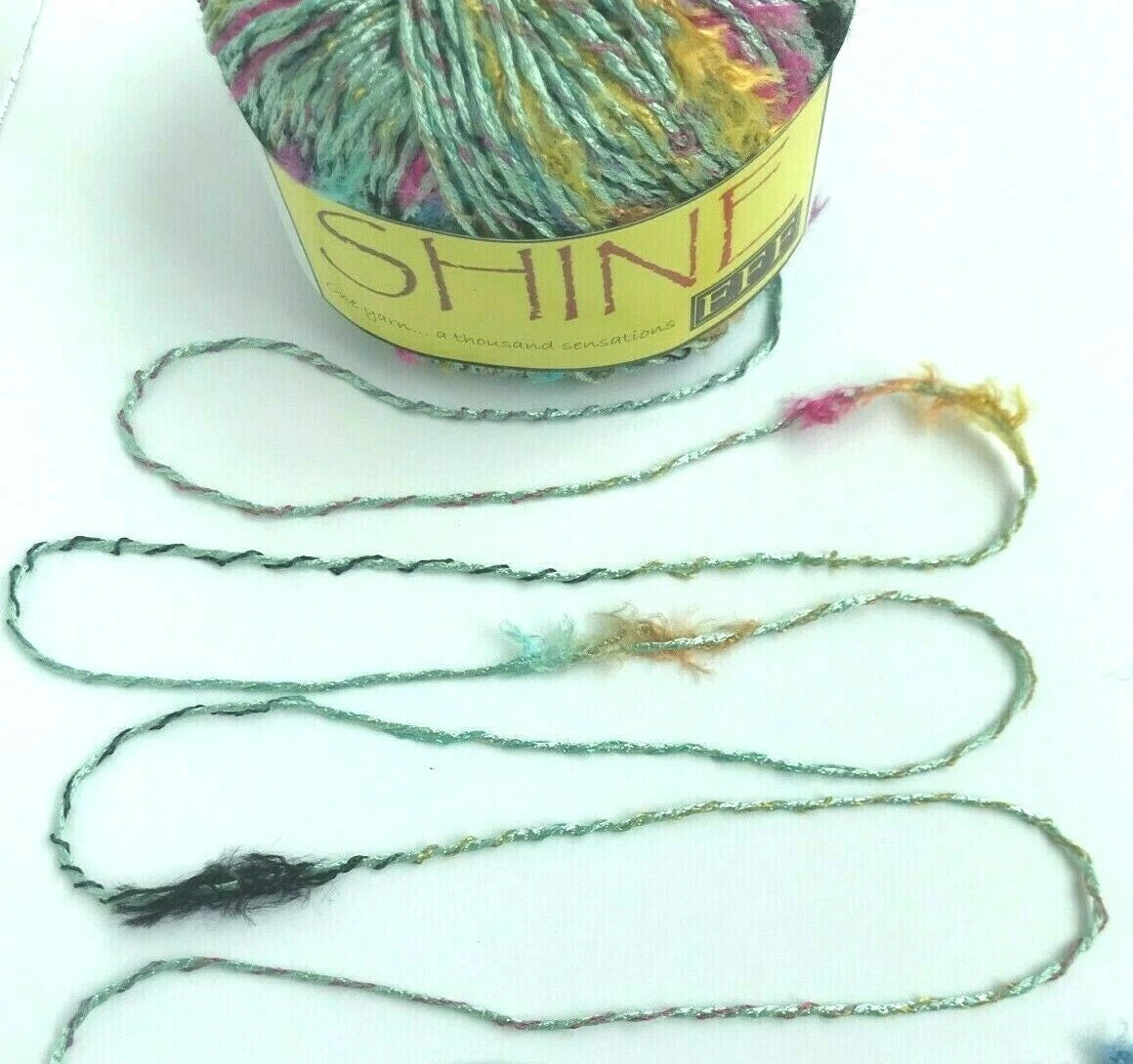 Ball of yarn with a long strand on a white background