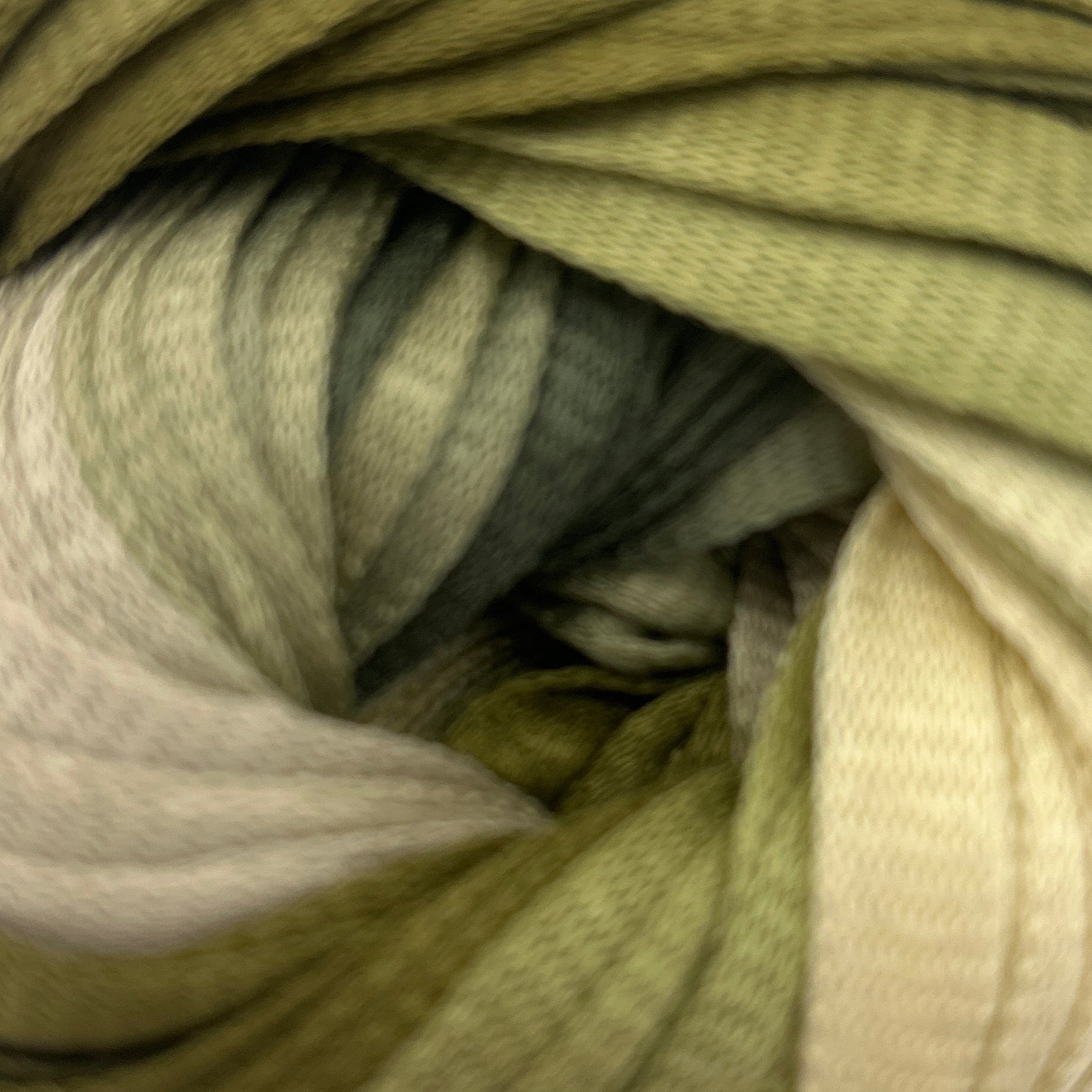 Ball of green and beige yarn on a white background