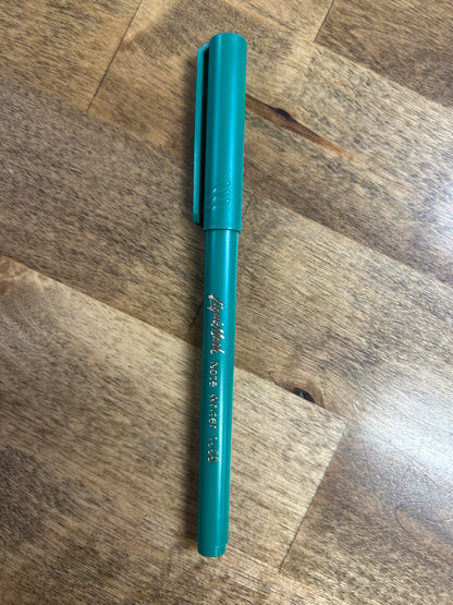 Teal pen on a wooden surface