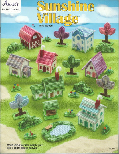 Cover of 'Sunshine Village' by Annie's Plastic Canvas with colorful village scene.