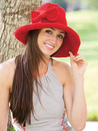 Woman wearing a red knit hat with a bow, standing outdoors.