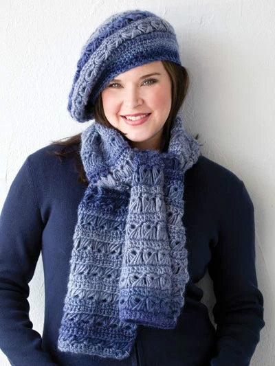 Woman wearing a blue crochet hat and scarf against a white background