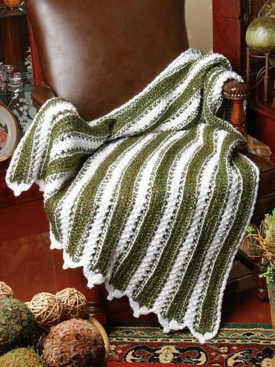 Green and white striped crocheted blanket draped over a chair in a home setting.