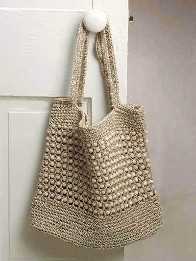 Beige woven bag with spherical patterns hanging on a white door handle.