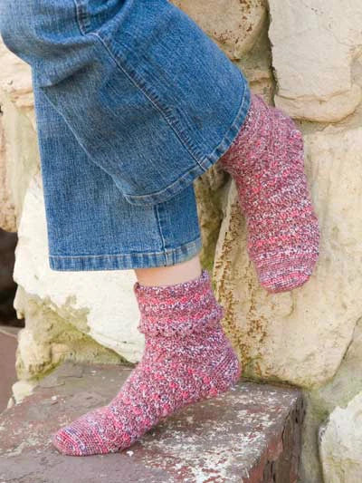 Person wearing pink socks and blue jeans standing on a stone surface.