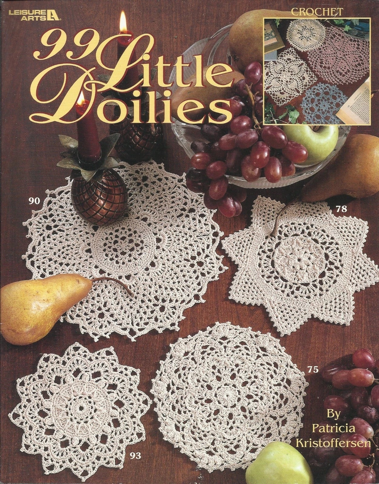 Book cover of '99 Little Doilies' with crochet doilies and fruits on a wooden surface.