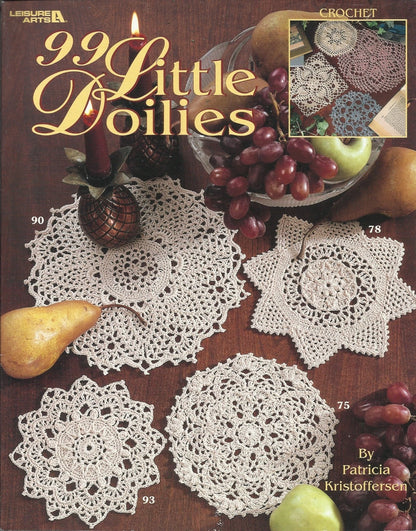 Book cover of '99 Little Doilies' with crochet doilies and fruits on a wooden surface.