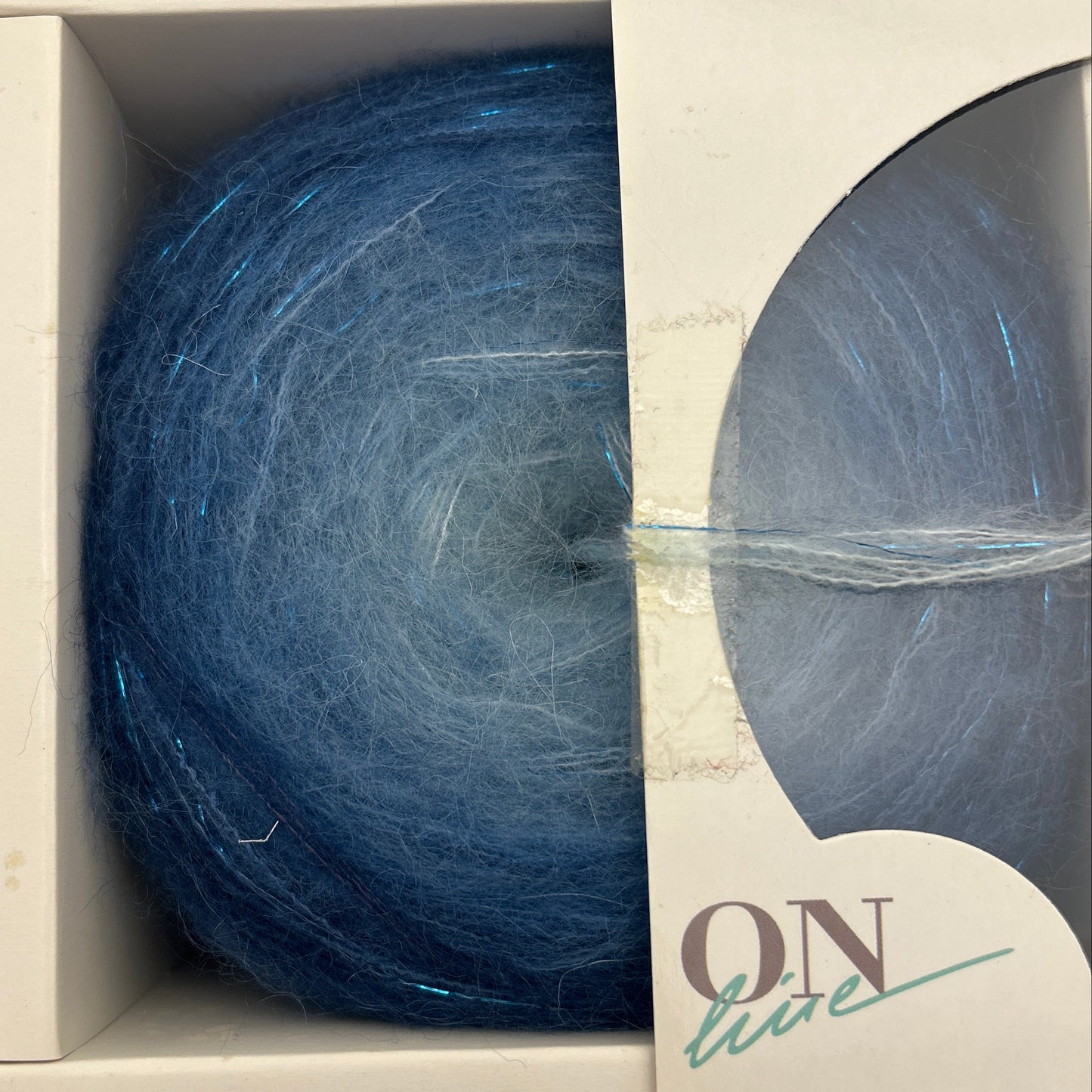 Blue yarn ball in a cardboard box with 'Nim' branding.