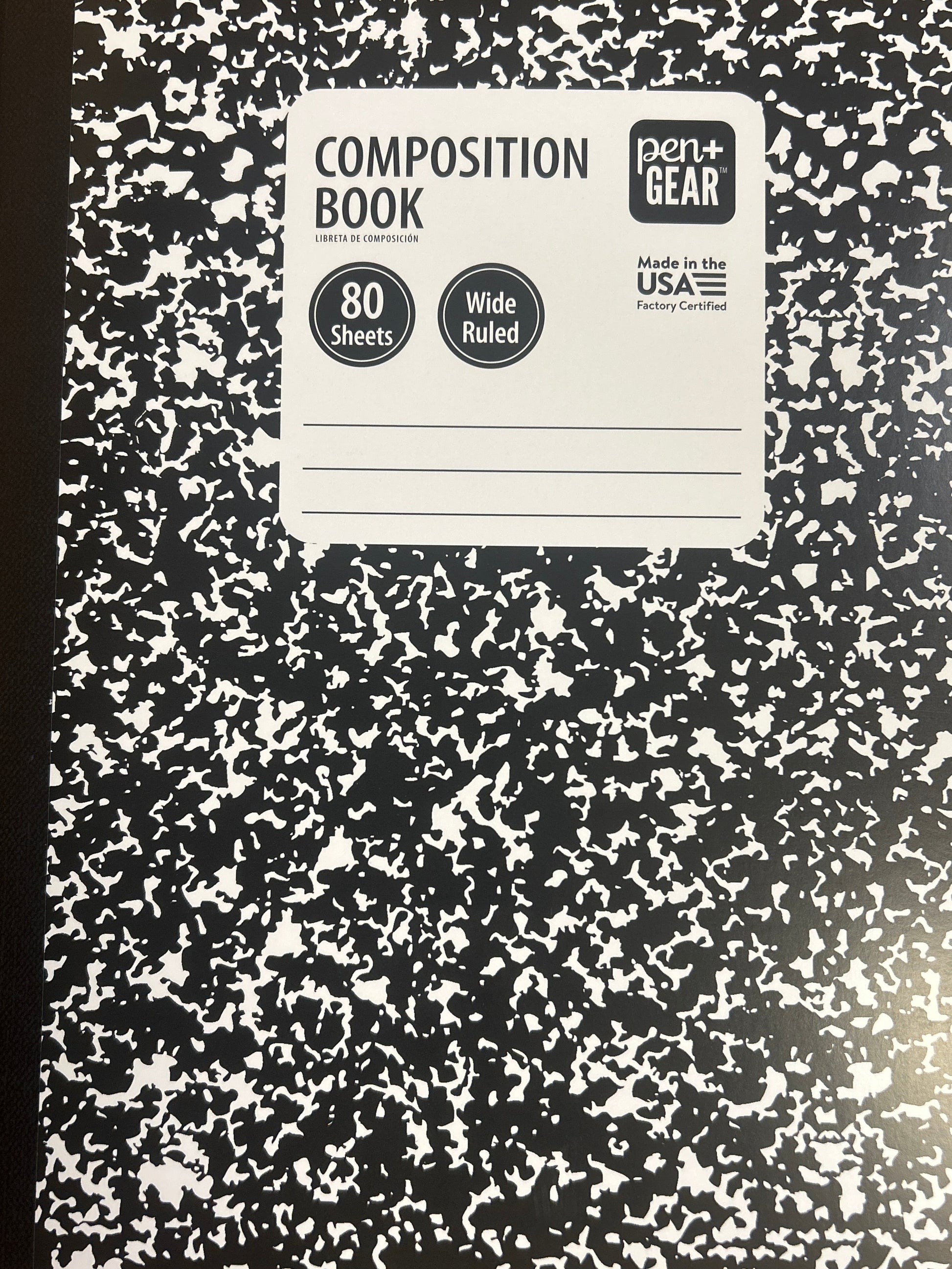 Composition book with black and white speckled cover on a wooden surface