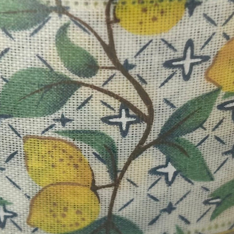 Close-up of a fabric pattern with lemons and leaves on a white background