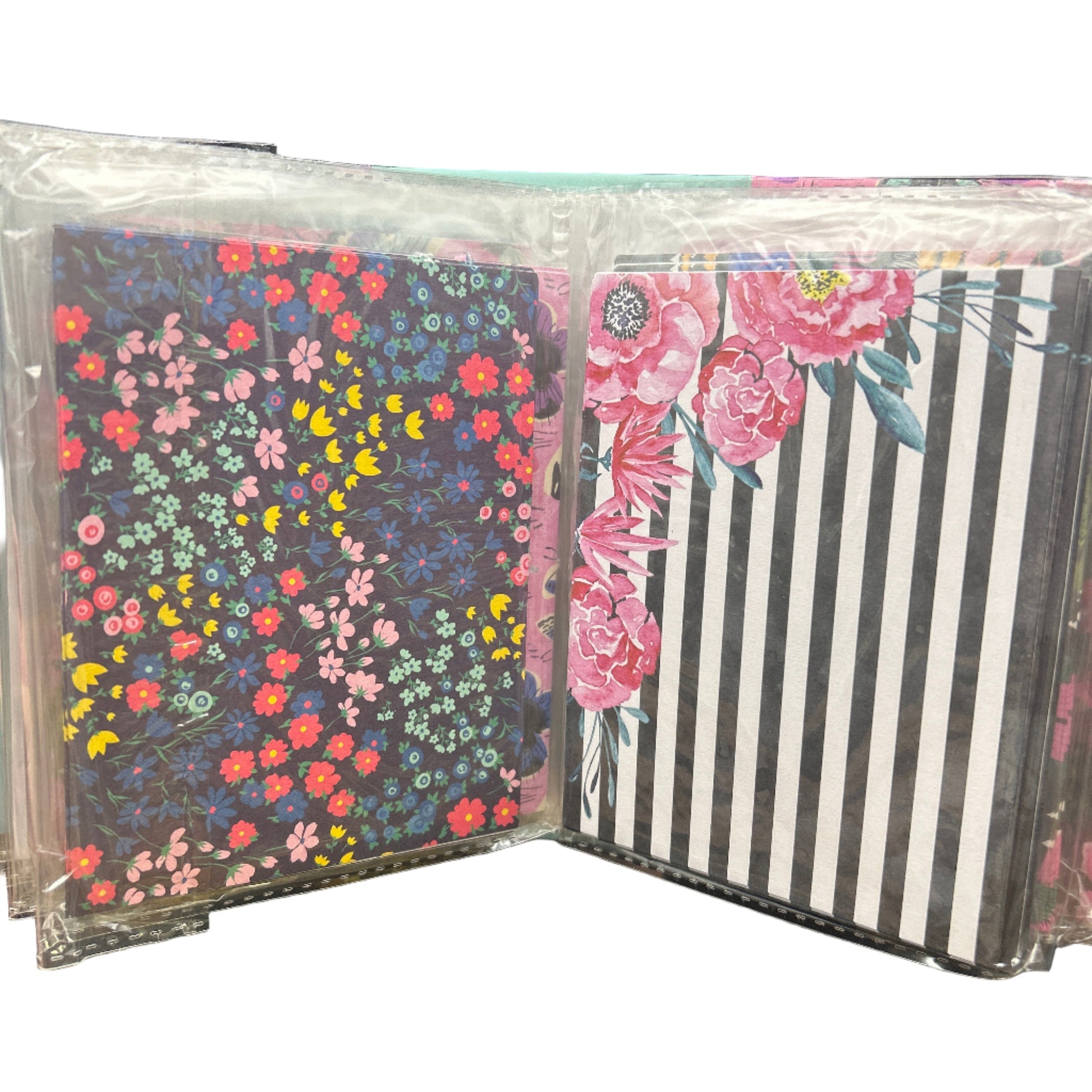 Stack of small notebooks with floral and striped designs on a dark surface