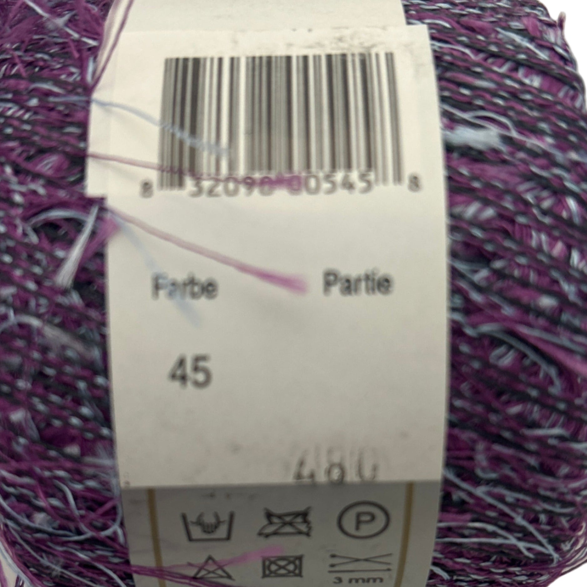 Ball of purple yarn with a label showing a barcode and text.
