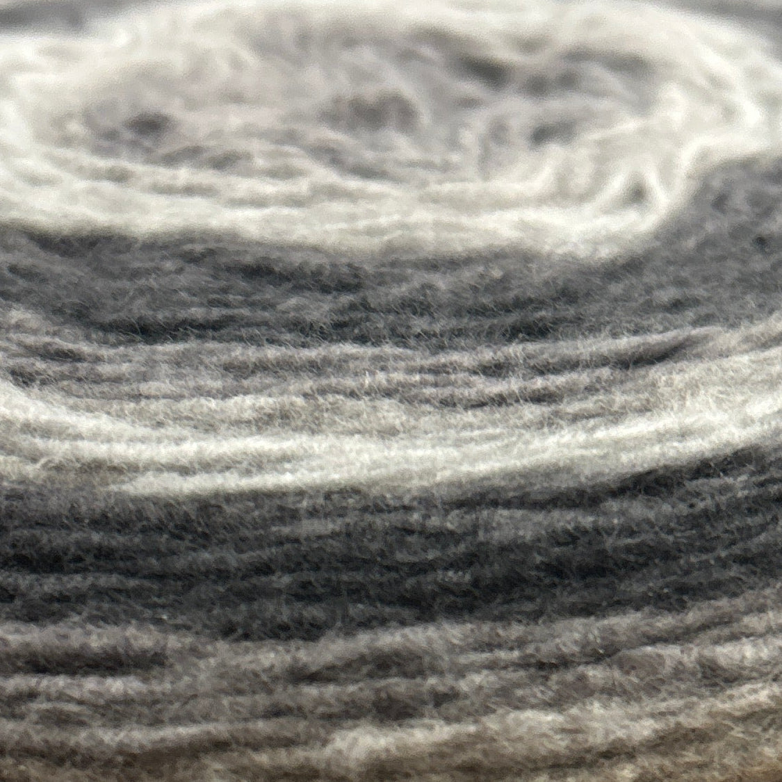 Spool of Caron Cloud Cakes yarn on a wooden surface with a blurred store background