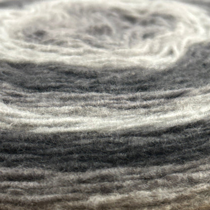 Spool of Caron Cloud Cakes yarn on a wooden surface with a blurred store background