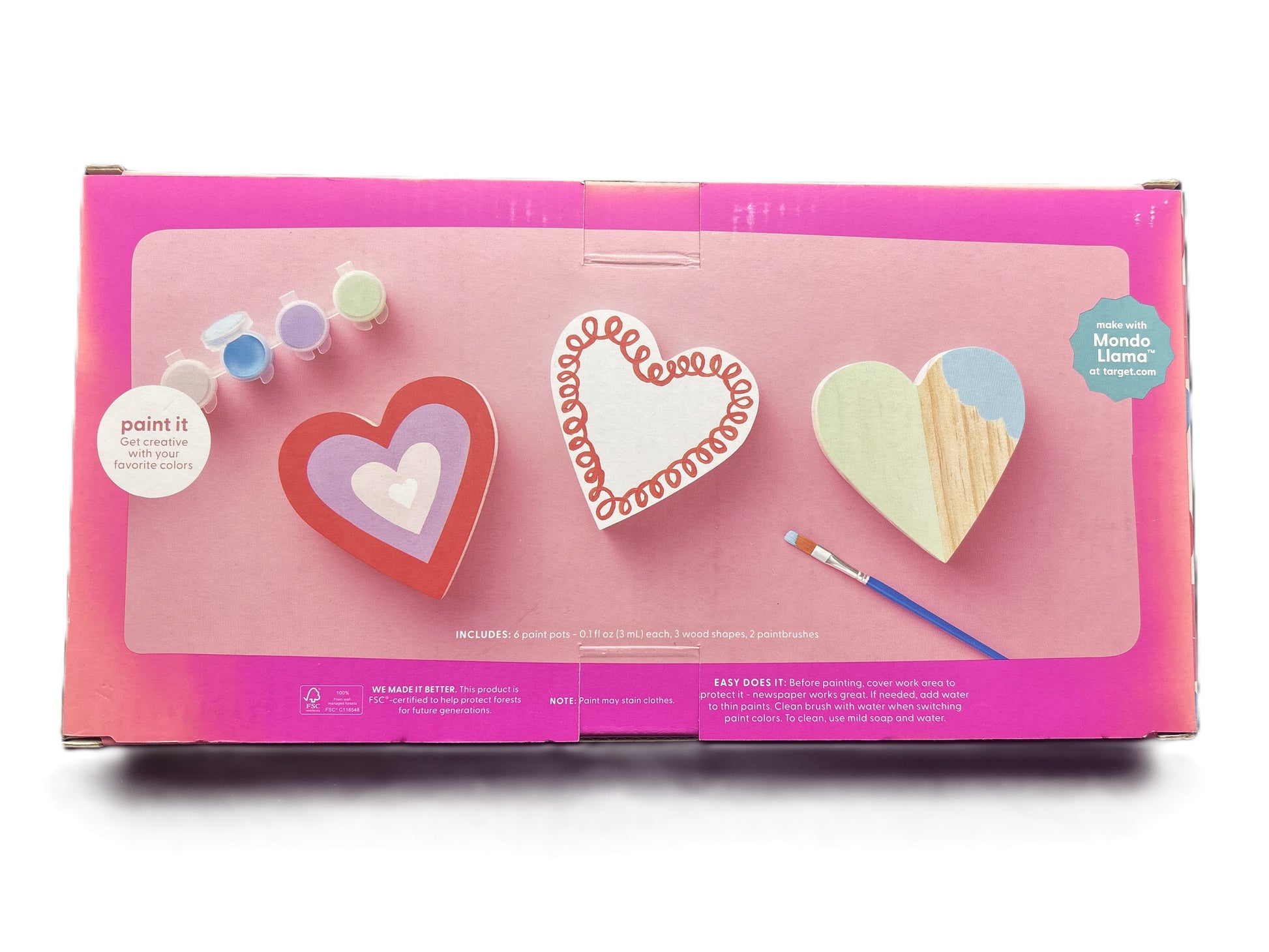Heart-shaped craft items with paintbrush and colors on a pink box