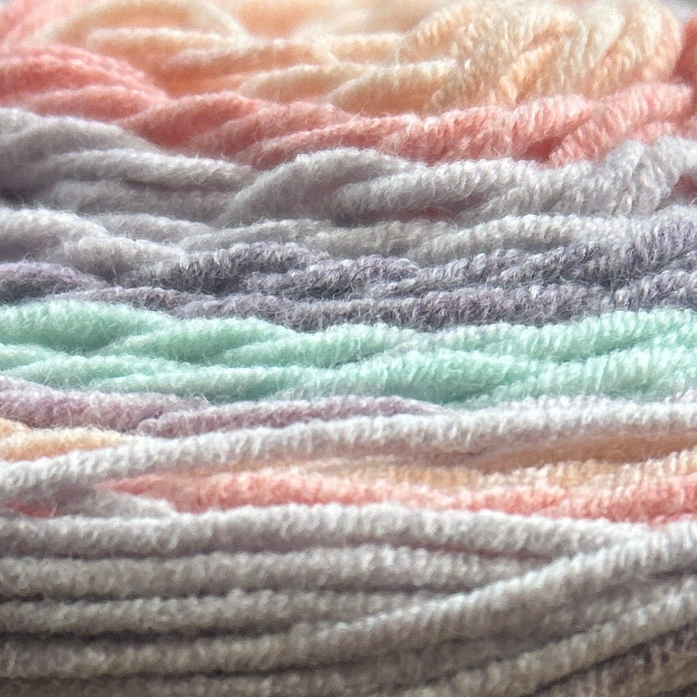 Spool of yarn with Caron label on a wooden surface