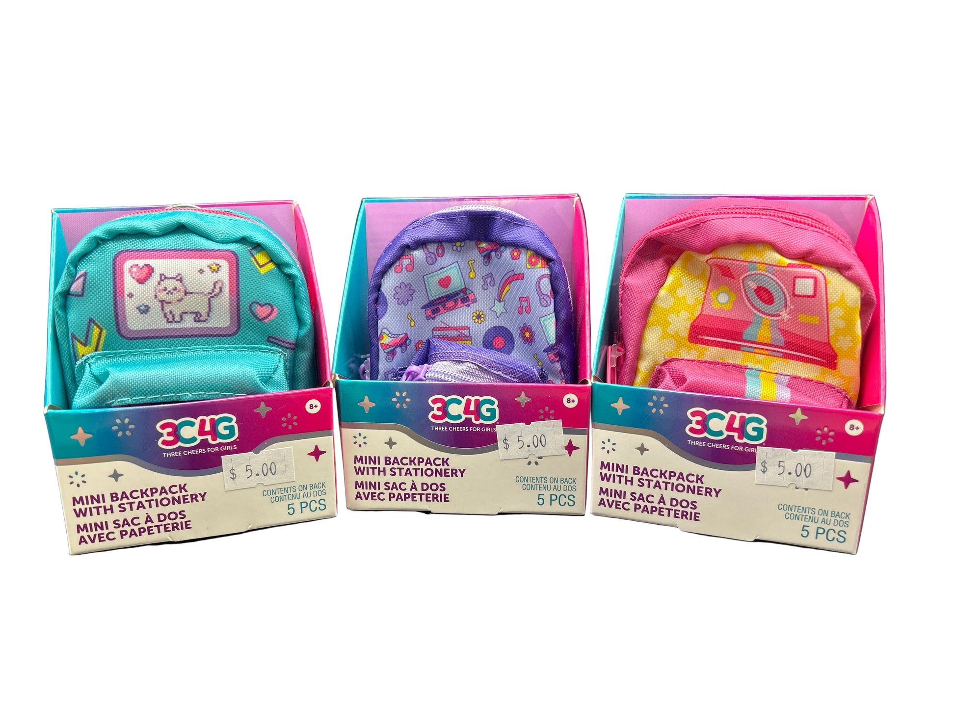 Three mini backpacks with stationery in packaging on a dark surface