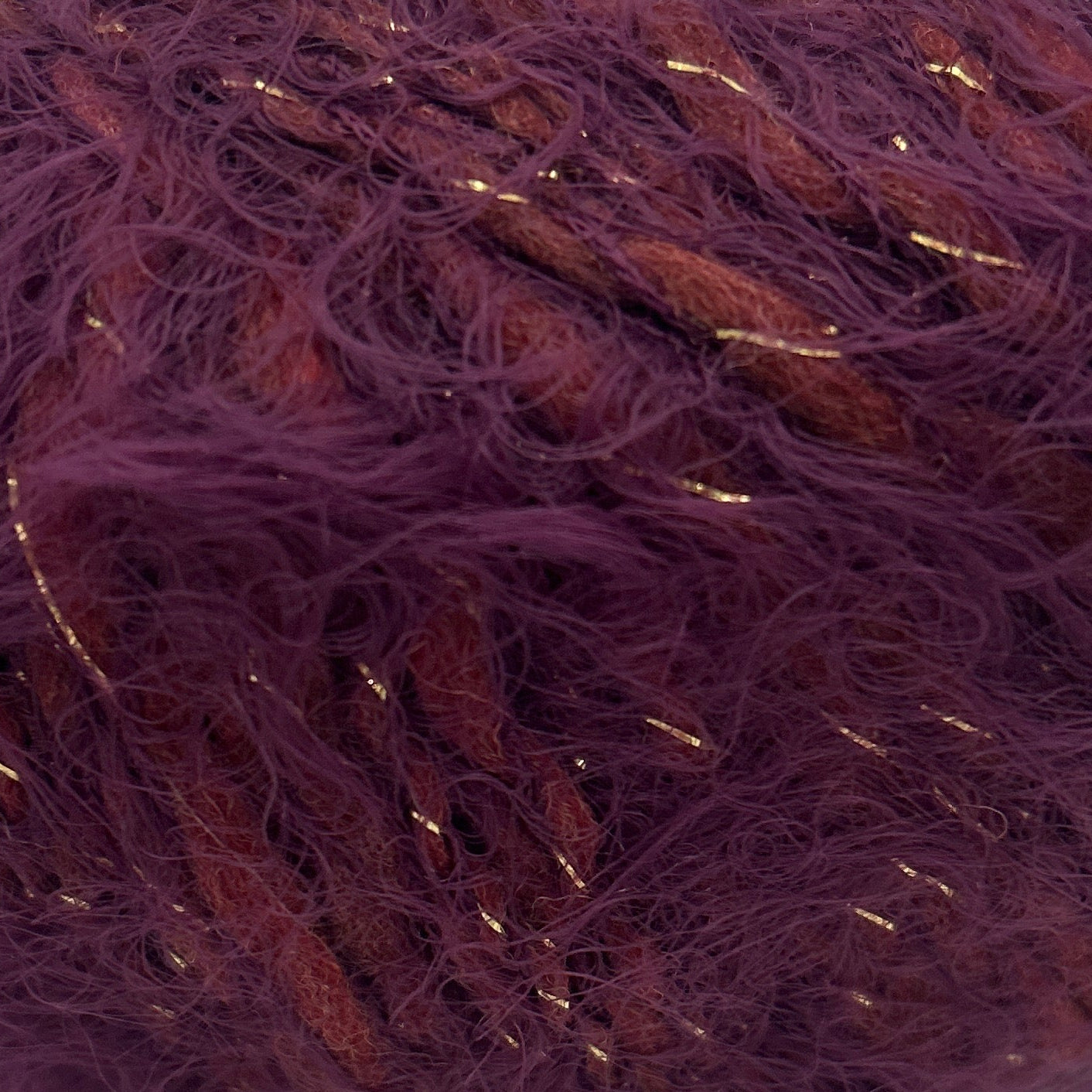 Purple yarn ball with gold threads on a white background