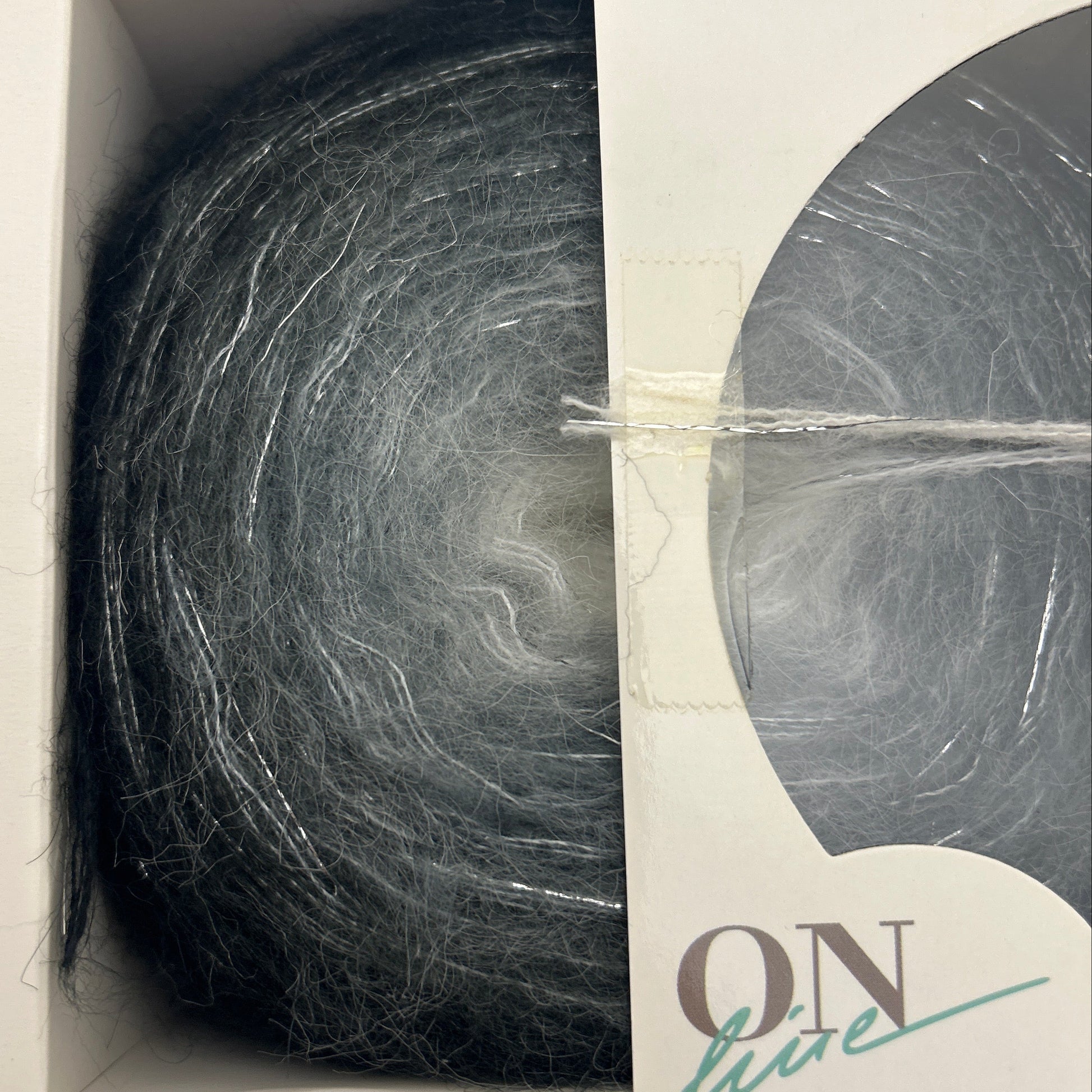 Ball of gray yarn in a cardboard box with 'Roz' branding.
