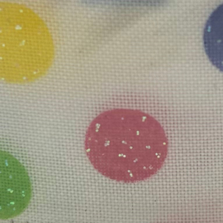 Close-up of fabric with colorful polka dots on a beige background