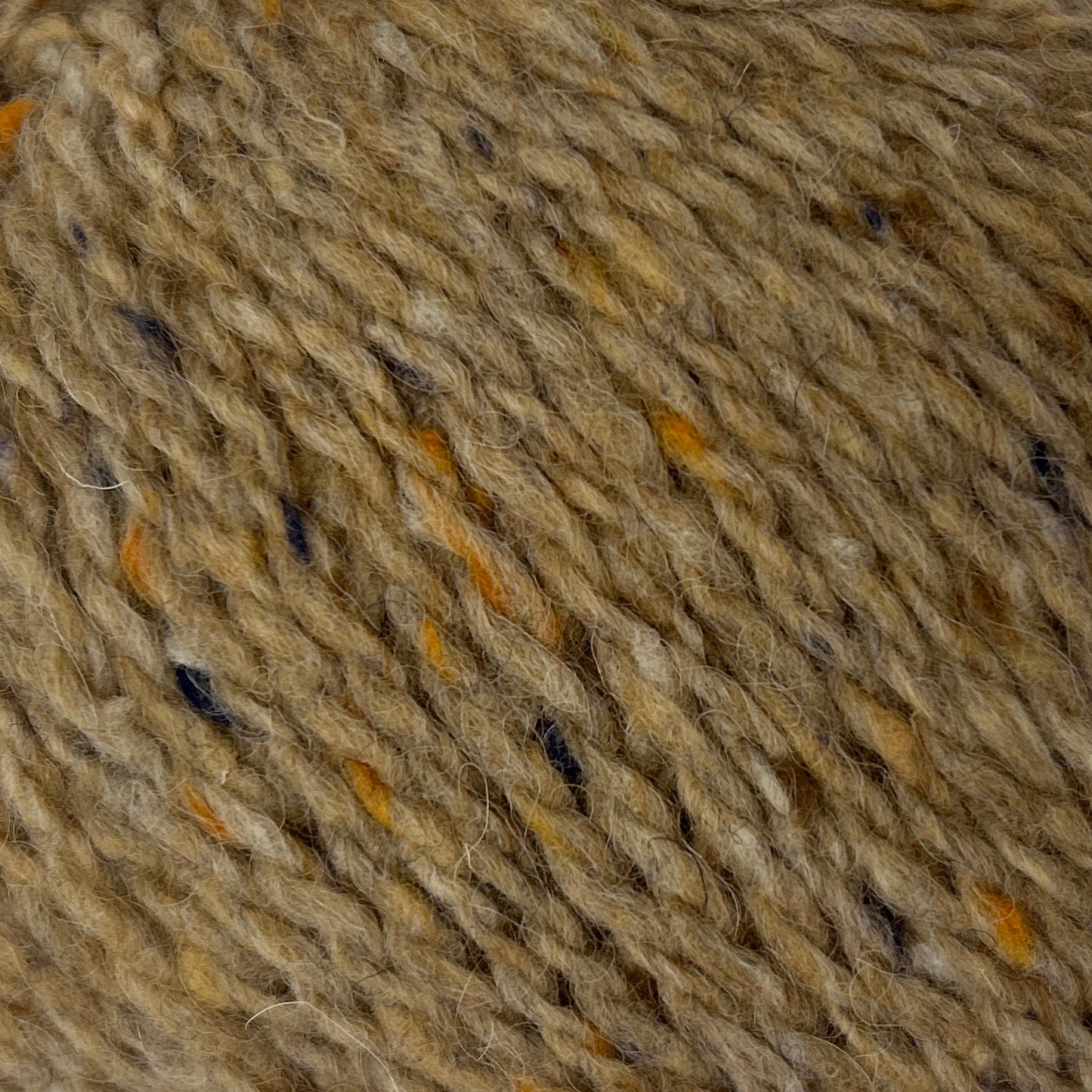 Ball of brown yarn with speckles on a white background