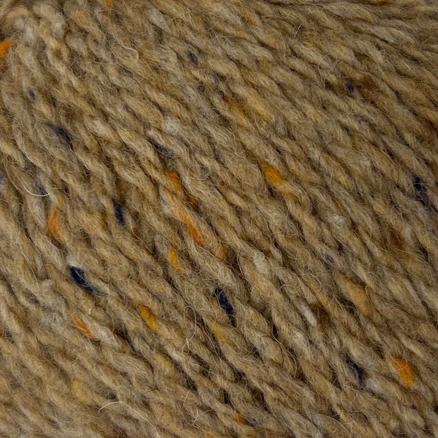 Ball of brown yarn with speckles on a white background