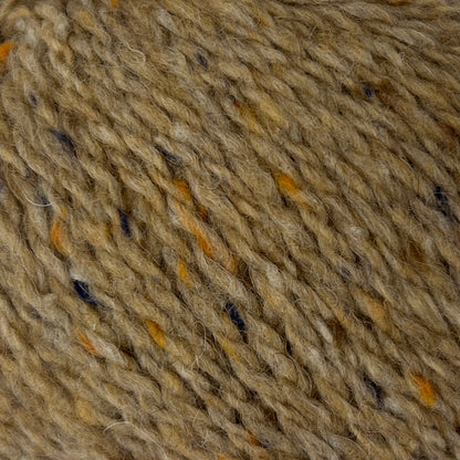 Ball of brown yarn with speckles on a white background