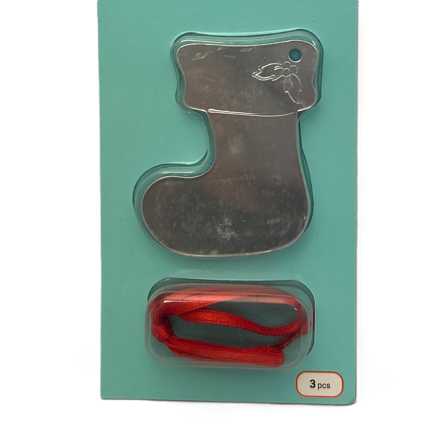 Metallic stocking-shaped cookie cutter with red ribbon in packaging on a teal background