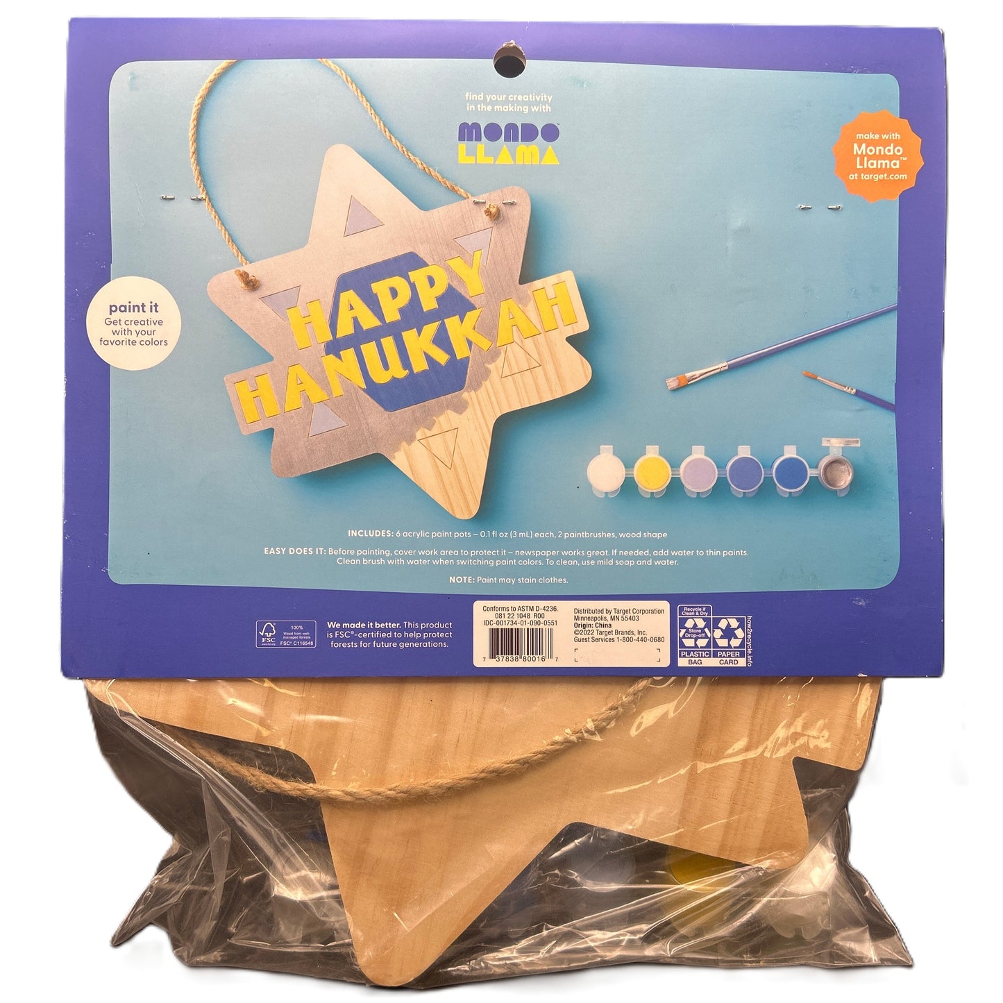 Happy Hanukkah craft kit with wooden star shape, paint bottles, and brushes on a blue background.