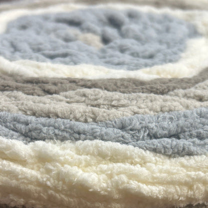 Roll of Bernat Baby Blanket yarn on a wooden surface