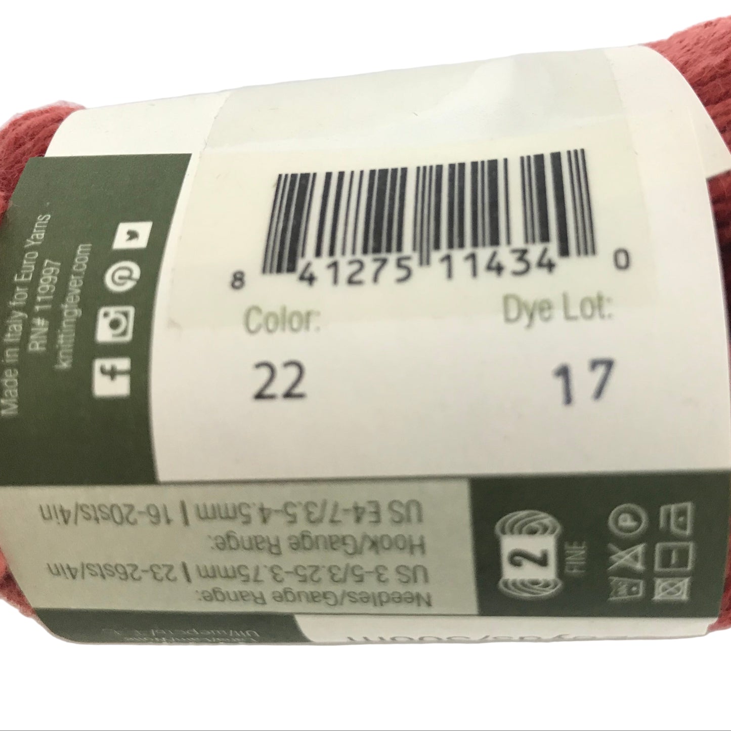 Red skein of yarn with a label showing product details on a white background