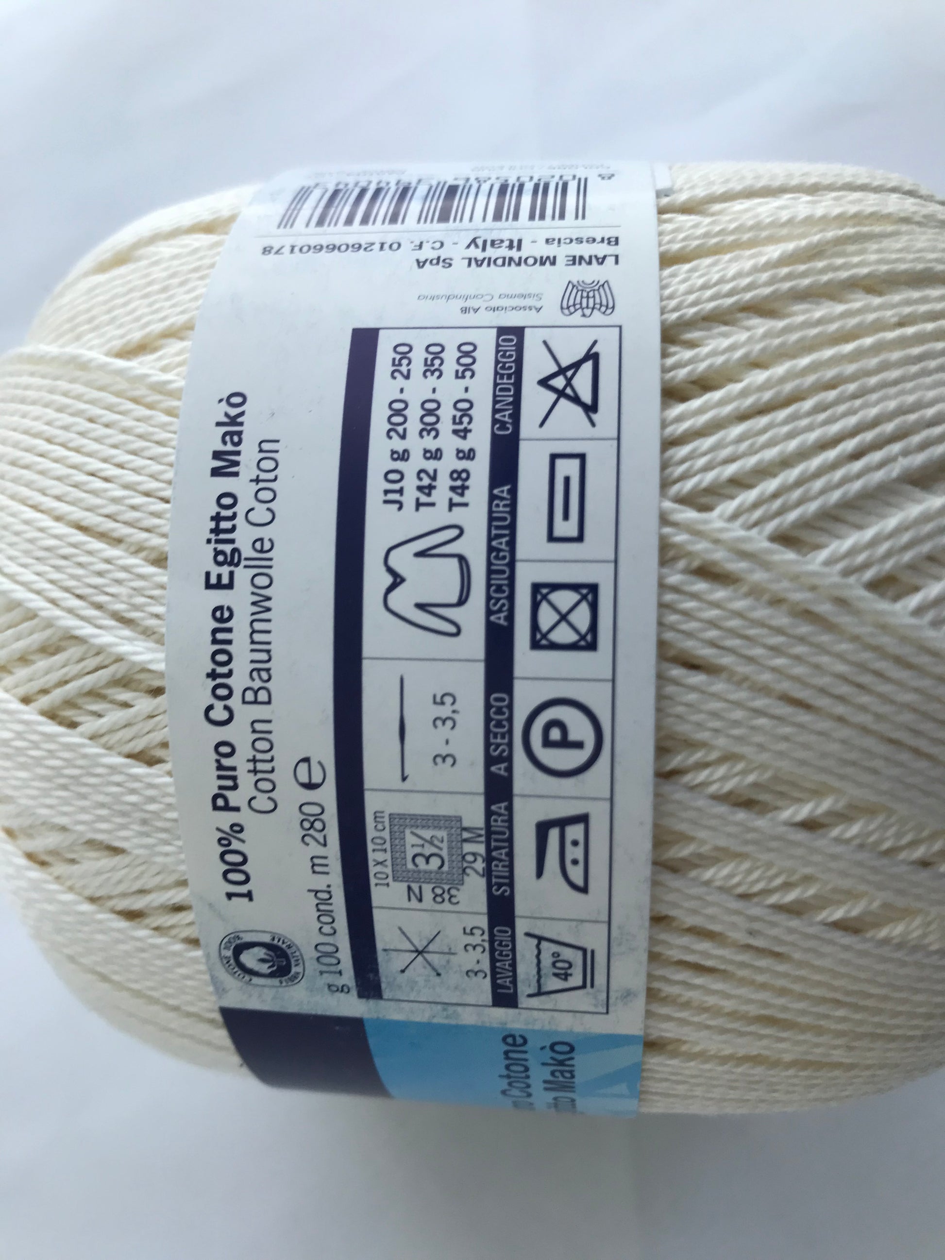 Ball of white yarn with a label on a light gray background