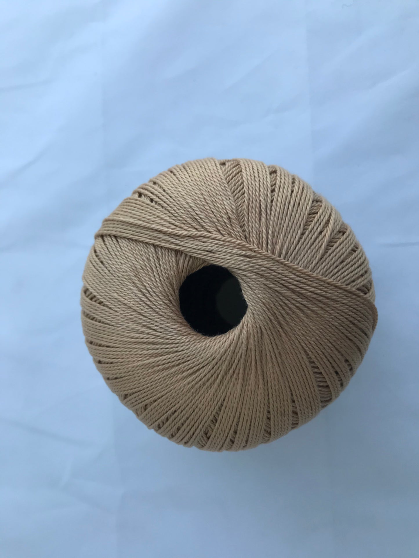 Beige spool of thread on a white background