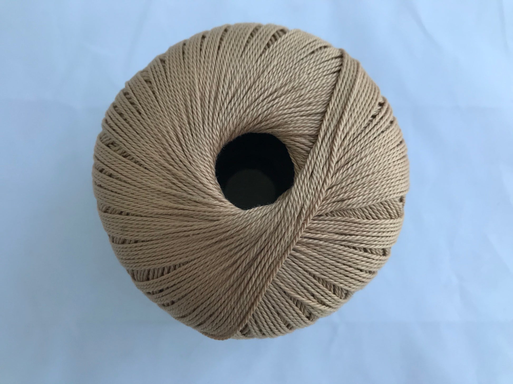 Ball of beige yarn on a light blue background