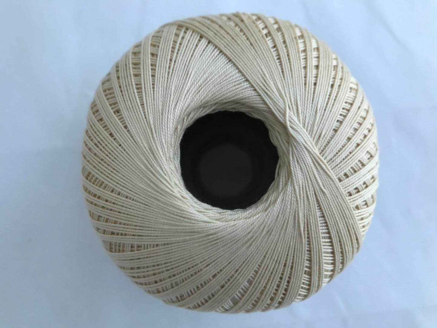 Spool of beige thread on a light blue background