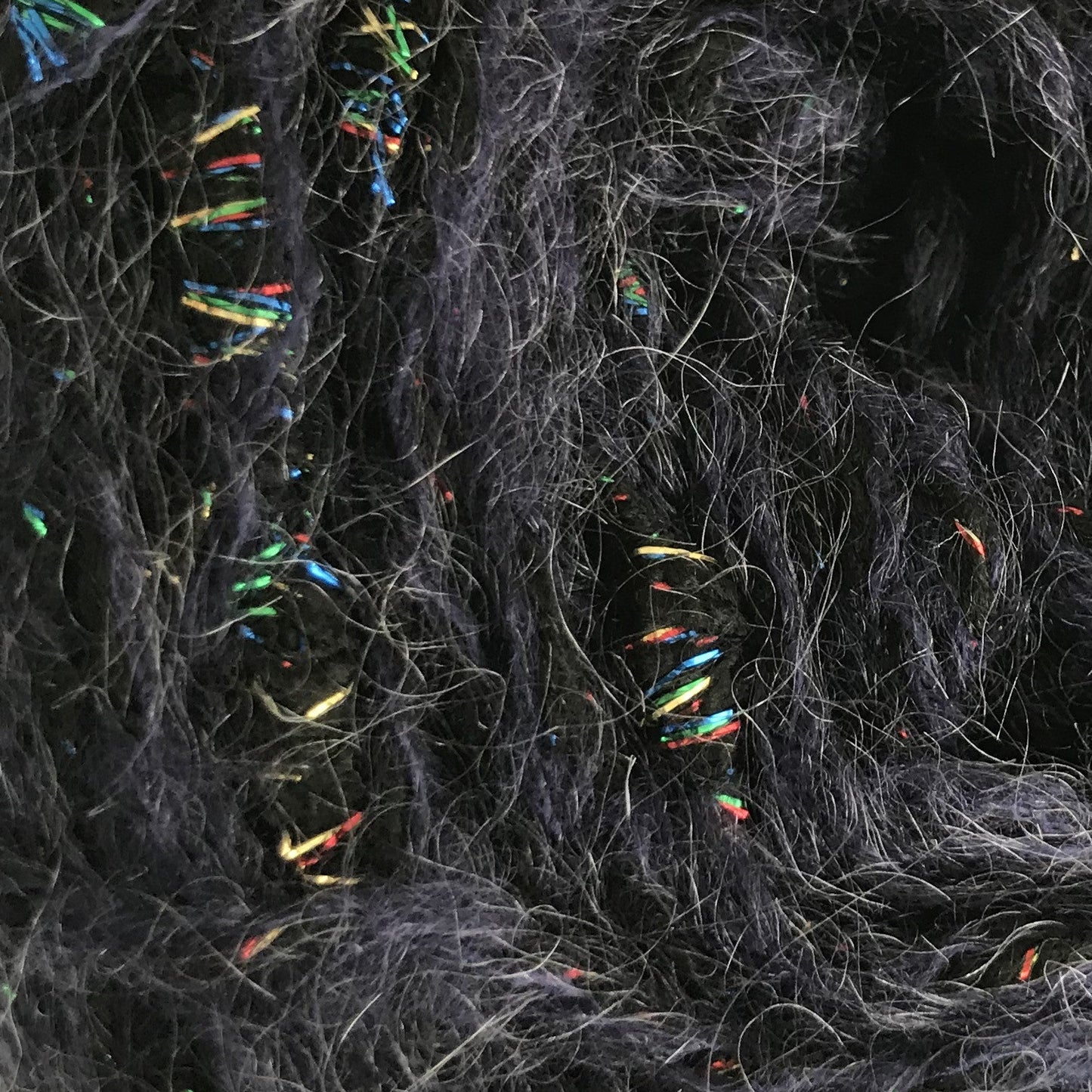 Ball of dark gray yarn with multicolored fibers on a white background