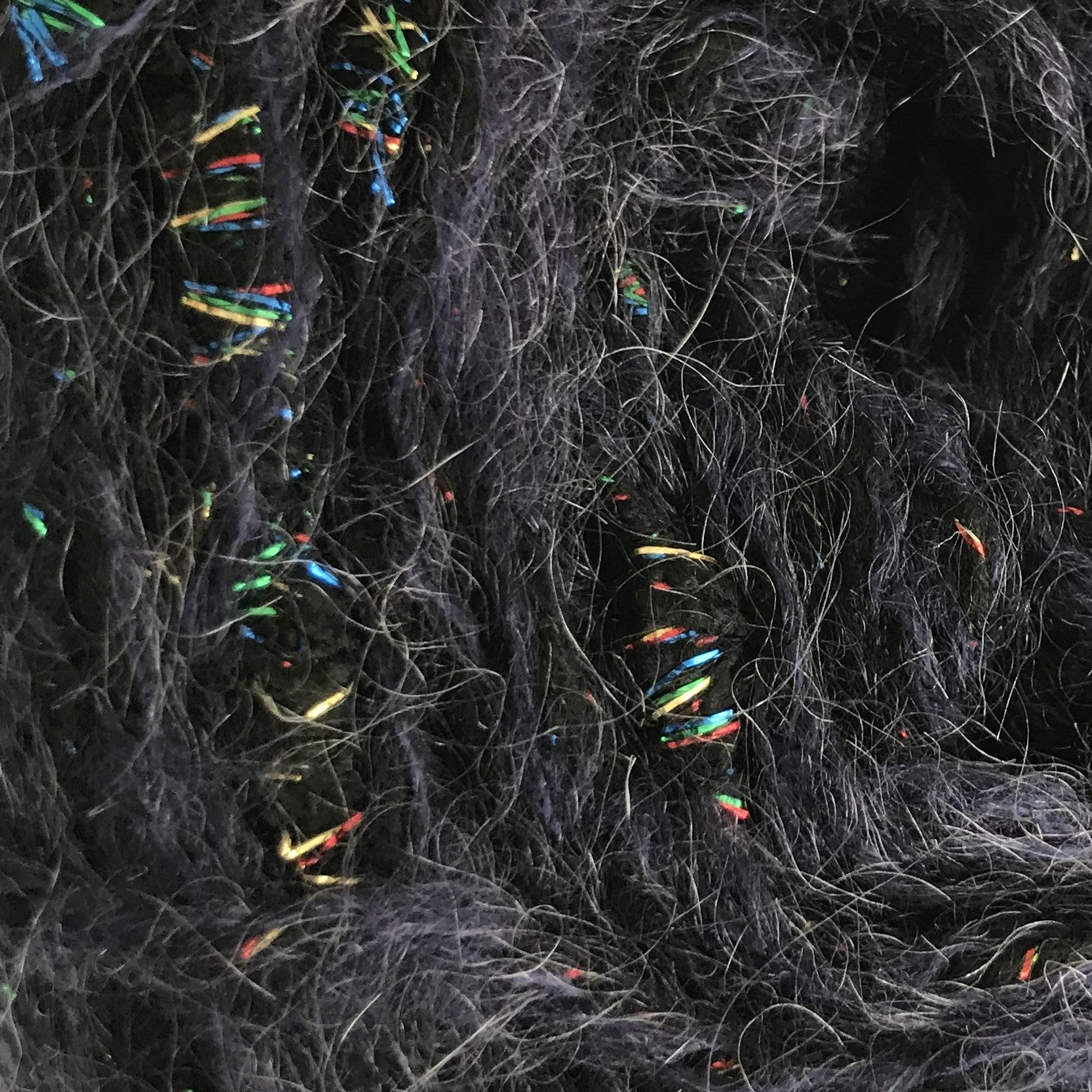 Ball of dark gray yarn with multicolored fibers on a white background
