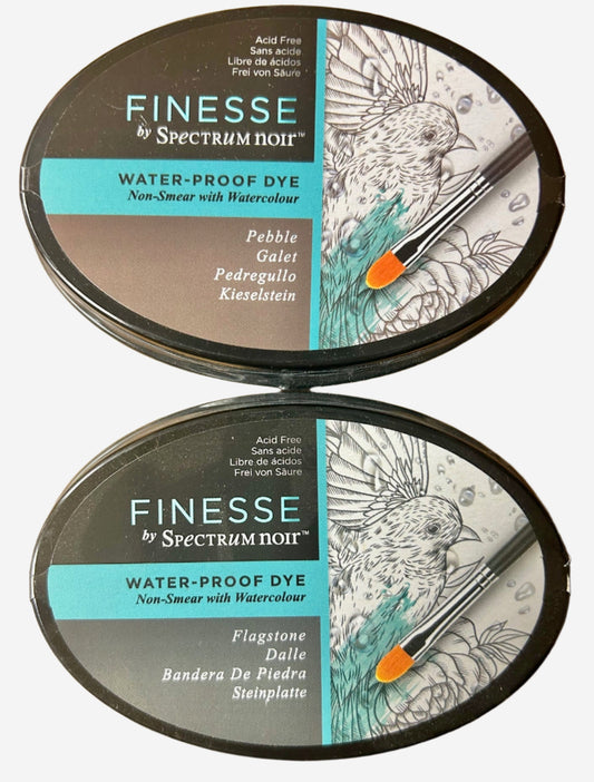 Two tins of Finesse by Spectrum Noir water-proof dye on a wooden surface.