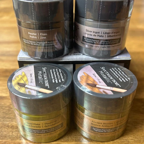Four containers of Spectralumin paint on a wooden surface