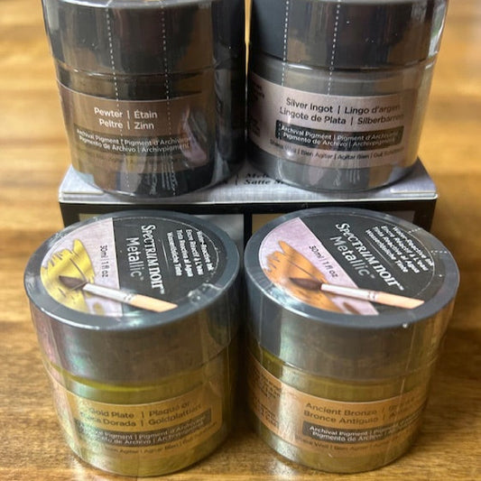 Four containers of Spectralumin paint on a wooden surface