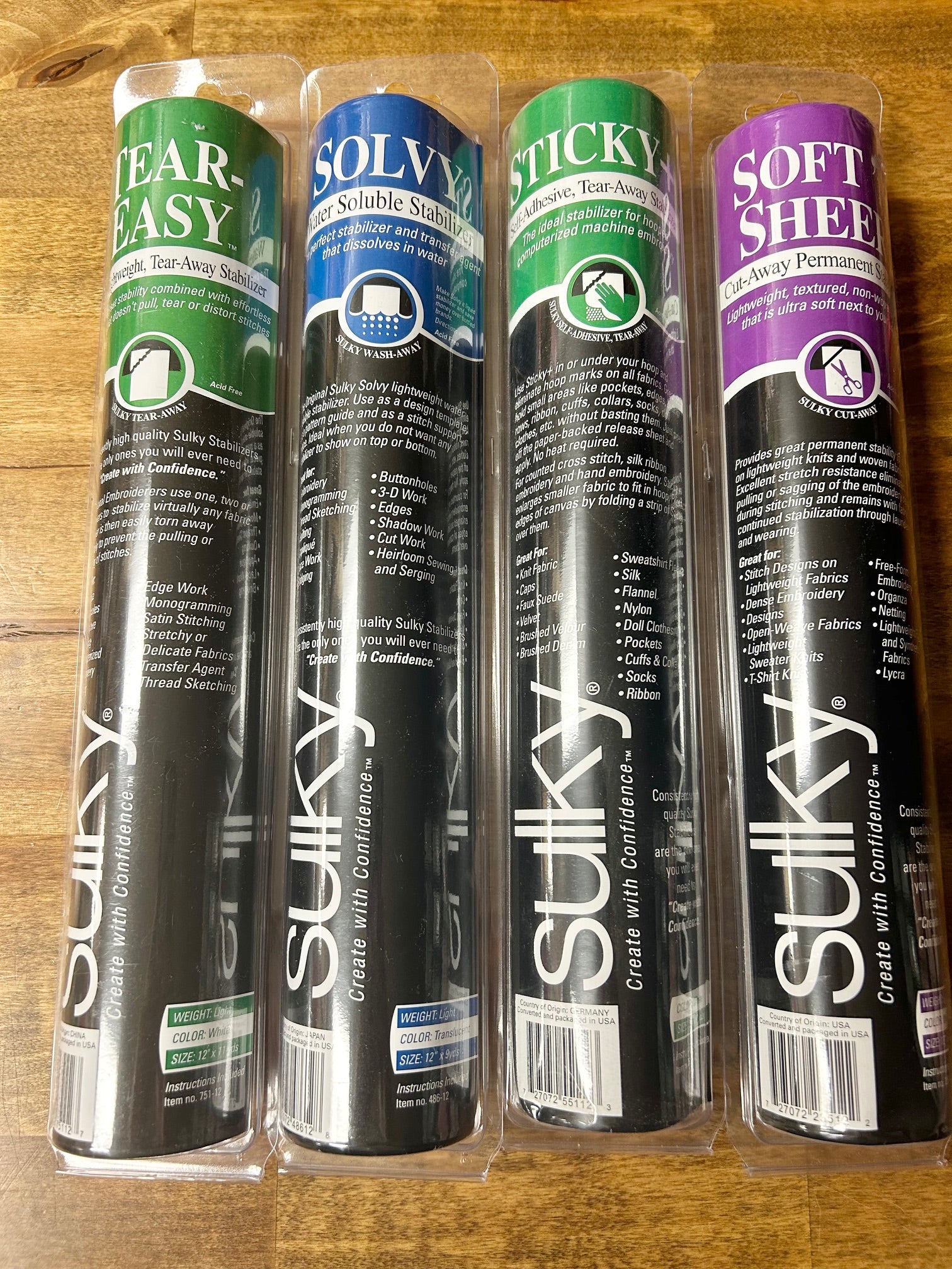 A high-quality image of four rolls of Sulky brand sewing and embroidery stabilizer products: Tear-Easy, Solvy water-soluble, Sticky self-adhesive tear-away, and Soft 'n Sheer cut-away.