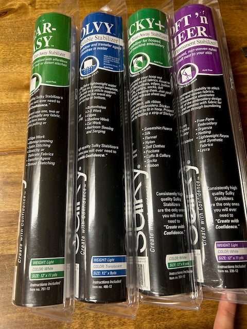 An image of several rolls of Sulky brand embroidery stabilizer products, including Tear-Easy, Soft'n Sheer, and Sticky types. 
