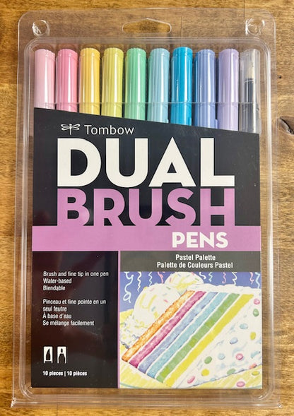 A box of 10 Tombow Dual Brush Pens in the Pastel Palette color set, featuring dual tips (brush and fine point) and water-based, blendable ink. The set includes colors such as carnation, pink, light ochre, pale yellow, mint, sky blue, process blue, mist purple, lilac, and cool gray. 