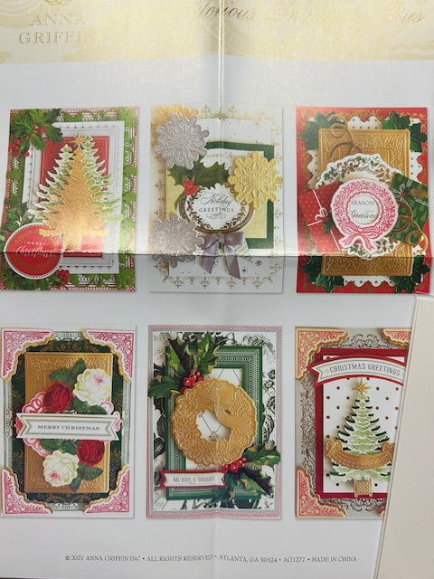 Six handmade holiday cards featuring intricate die-cut designs including Christmas trees, wreaths, and floral elements, created using Anna Griffin's 3D concentric frame dies.