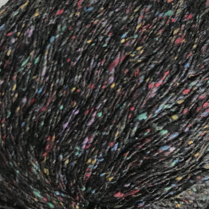 Close-up of speckled yarn ball with multicolor specks on a black background